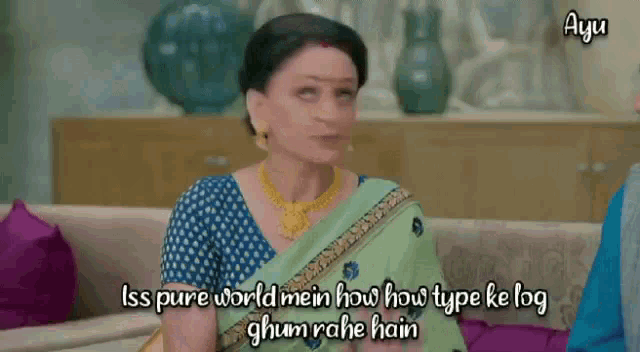 a woman in a green saree is sitting on a couch and talking