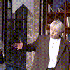 a man in a suit is standing in front of a bookcase