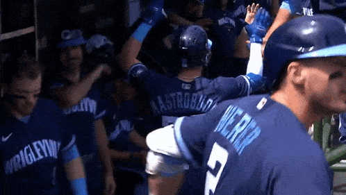 a baseball player with the number 5 on his back is surrounded by his teammates .