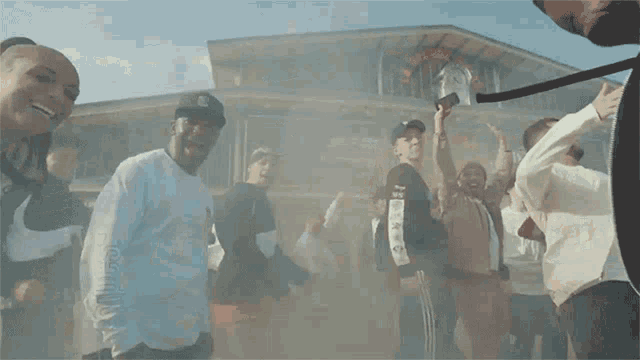 a group of people are dancing in front of a building with smoke coming out