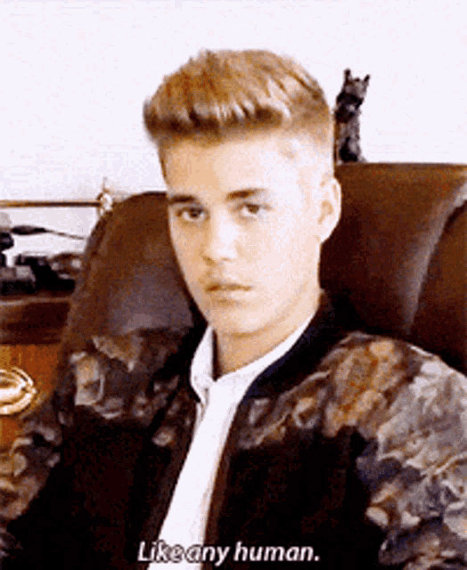 a young man sitting in a chair with the words like any human written below him