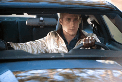 a man in a white jacket is driving a blue car