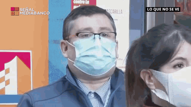 a man wearing a face mask stands next to a woman
