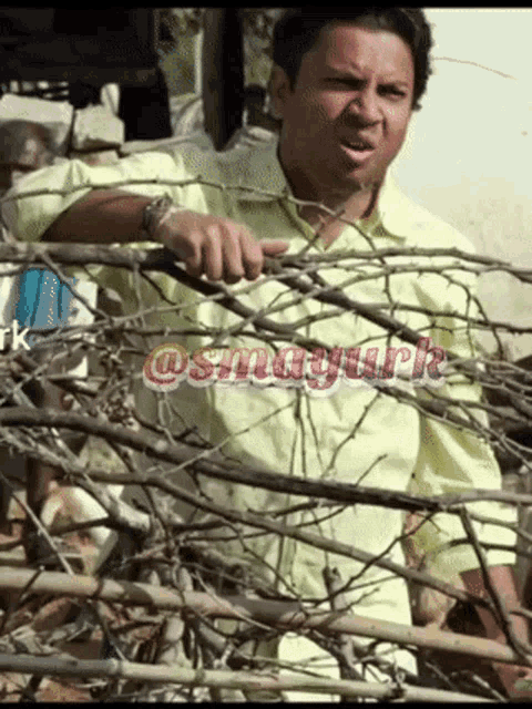 a man in a yellow shirt is standing behind a barbed wire fence with the hashtag @smagurk