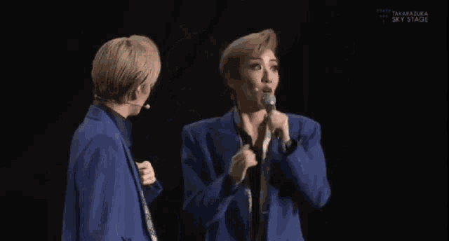 a man and a woman are standing next to each other on a stage holding microphones .