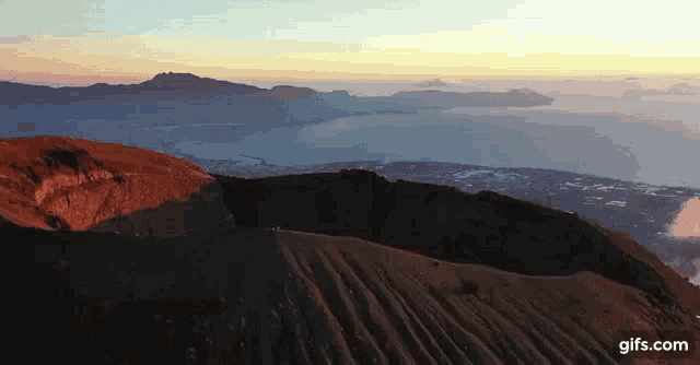 an aerial view of a volcano at sunset with a lake in the background
