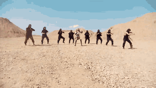 a group of people are dancing in a desert