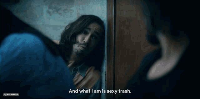 a man leaning against a wall with the words " and what i am is sexy trash " next to him
