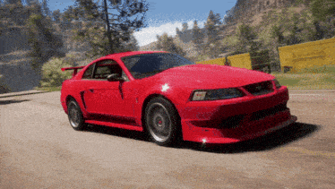 a red ford mustang is driving down a road with mountains in the background