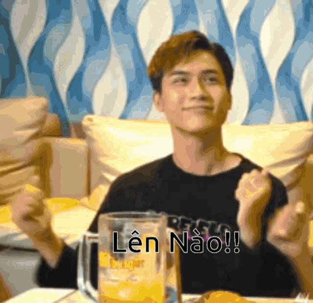 a man is sitting at a table with a glass of beer and a sign that says len nao !
