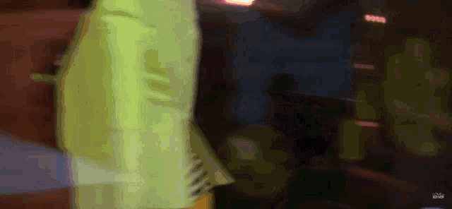 a woman in a neon green dress is standing in front of a dark room .