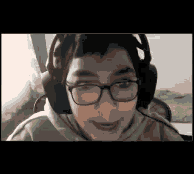 a young boy wearing glasses and headphones is looking at the camera .