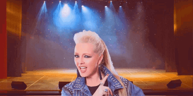 a woman in a studded denim jacket is pointing at something