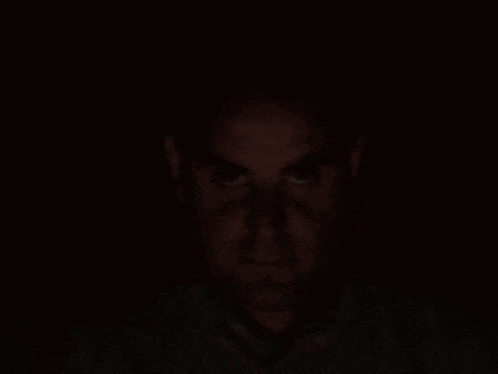 a man 's face is shown in the dark with a shadow on his face