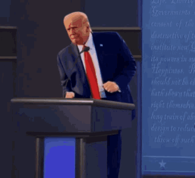 a man in a suit and tie stands at a podium