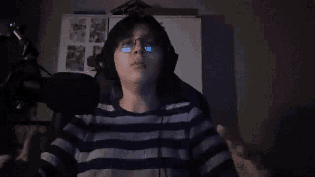 a person wearing glasses and headphones is talking into a microphone .