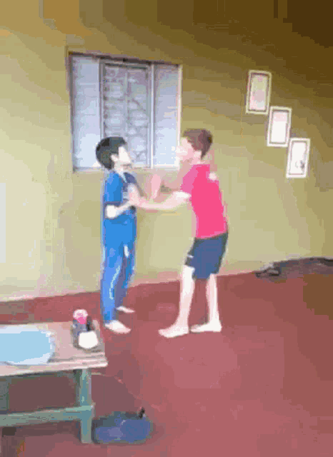 a boy in a red shirt is fighting another boy in a blue shirt in a living room