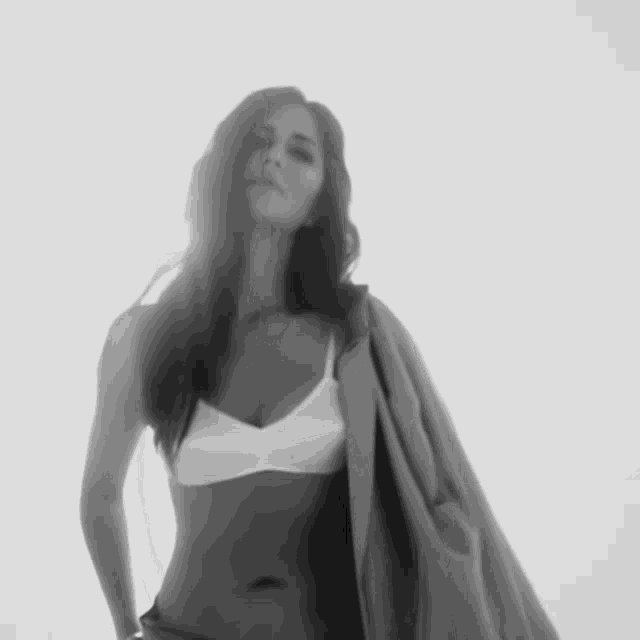 a woman in a white bra is holding a jacket over her shoulder