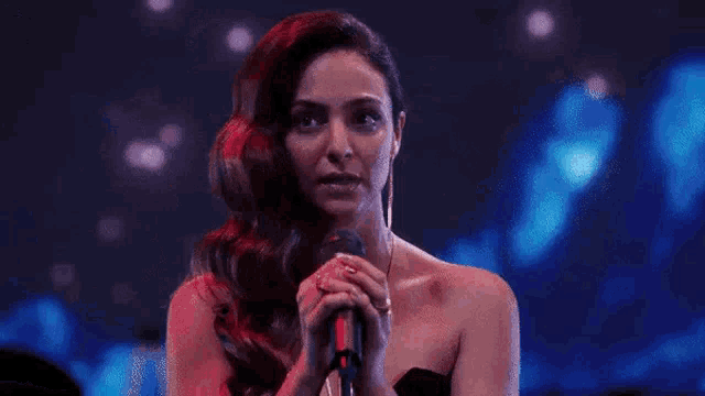 a woman in a black dress is singing into a microphone .