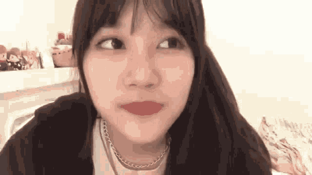 a close up of a young woman making a funny face while wearing a necklace .