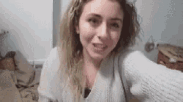 a woman is taking a selfie in a bedroom and smiling .