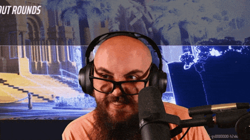 a man wearing headphones and glasses stands in front of a microphone with the words out rounds on the screen behind him