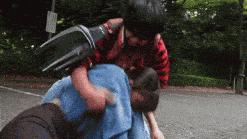two people are fighting in a parking lot with a sign in the background that says " no parking "