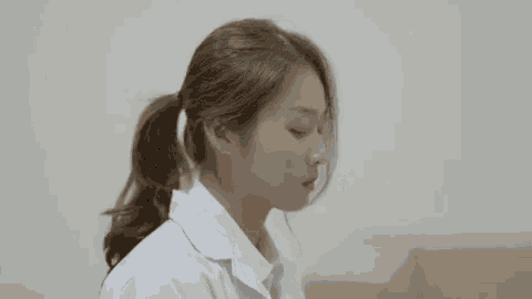 a woman in a white lab coat is sitting on a couch with her eyes closed .