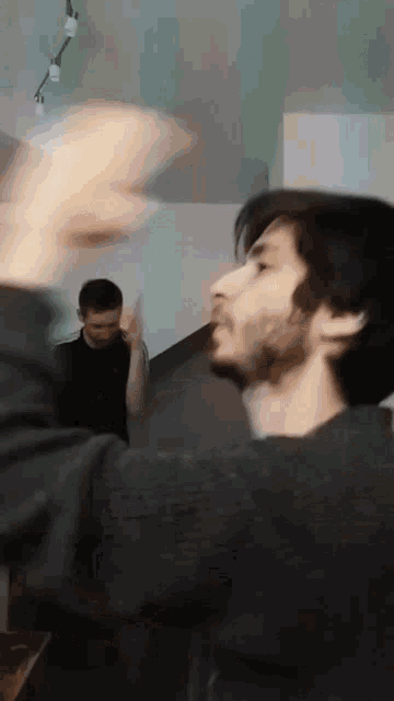 a man with a beard is standing in front of another man who is standing in the background