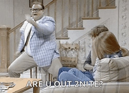 a man is jumping in the air while a woman sits on a couch and says `` are u out 2nite ? ''