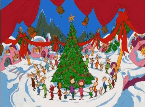 a group of people are standing around a christmas tree holding hands