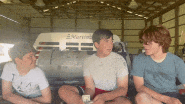 three boys are sitting in front of a martin vehicle