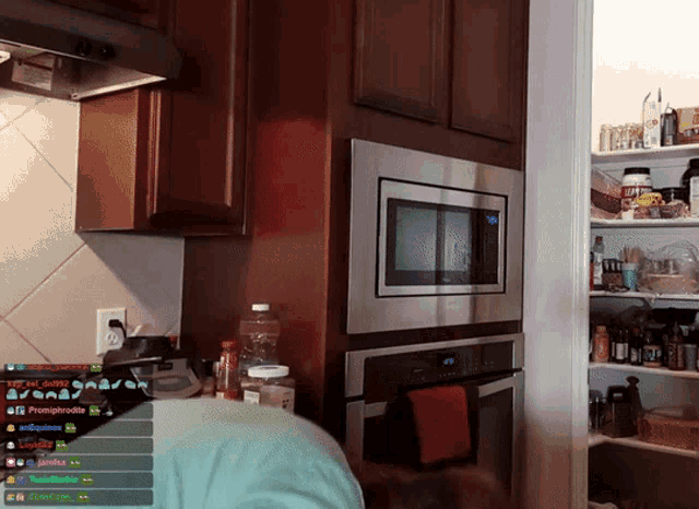 a kitchen with a stainless steel microwave and a few shelves with bottles on them