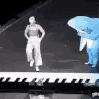 a man in a shark costume is standing next to a woman in a shark costume on a stage .