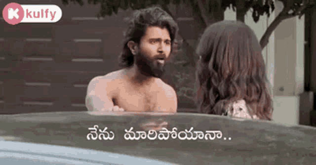 a shirtless man is standing next to a woman in a car and talking to her .