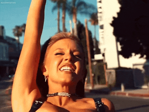 a woman is smiling with her arms in the air and the word resident evils is visible in the corner
