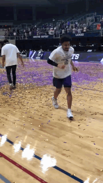 a man wearing a shirt that says ' houston baptist ' on it runs on a basketball court
