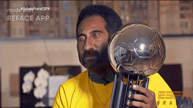 a man in a yellow shirt is holding a trophy that says reface app on the bottom