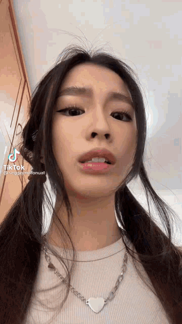 a close up of a woman wearing a white shirt and a necklace .
