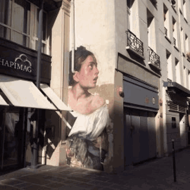 a painting of a woman on the side of a building next to a chapimag store