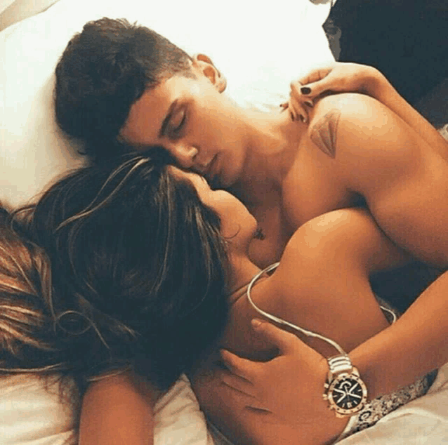 a man wearing a rolex watch is hugging a woman on a bed