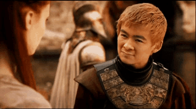 a young man in armor talks to a woman