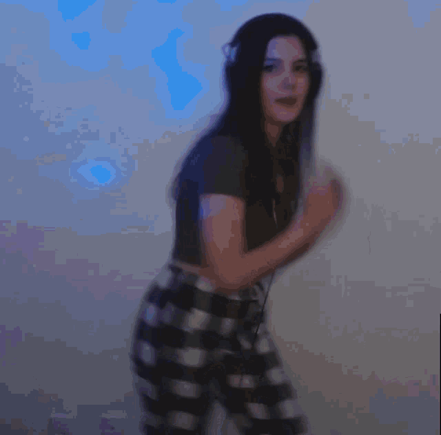 a blurry picture of a woman in a black shirt and plaid pants dancing .