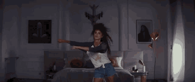 a woman is standing in front of a bed wearing a t-shirt that says queen