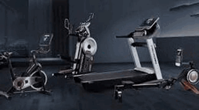 a row of treadmills in a gym with monitors .