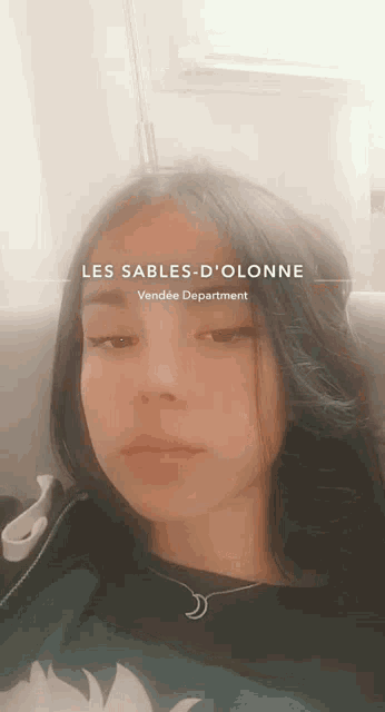 a girl is sitting on a couch with the words les sables-d'olonne on her face