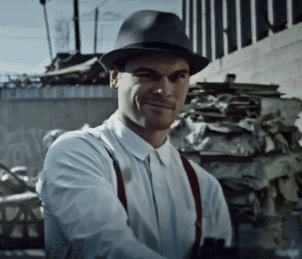 a man wearing a hat and suspenders smiles for the camera