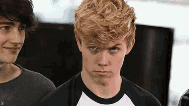 a boy with blonde hair looks at the camera with a serious look on his face