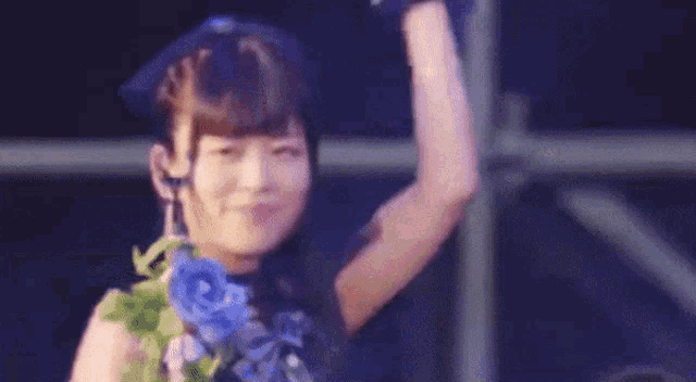 a woman is dancing on a stage with a microphone in her hand and flowers in her hair .