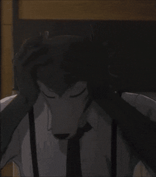 a man in a suit and tie with a wolf mask on his face is covering his face with his hands .